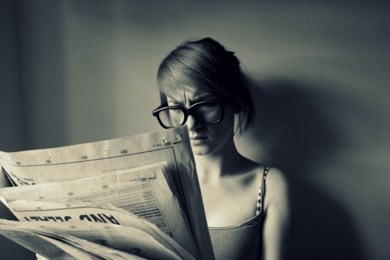 Девушка держит развернутую иностранную газету. Фото рубрика читали, смотрели. Playing paper